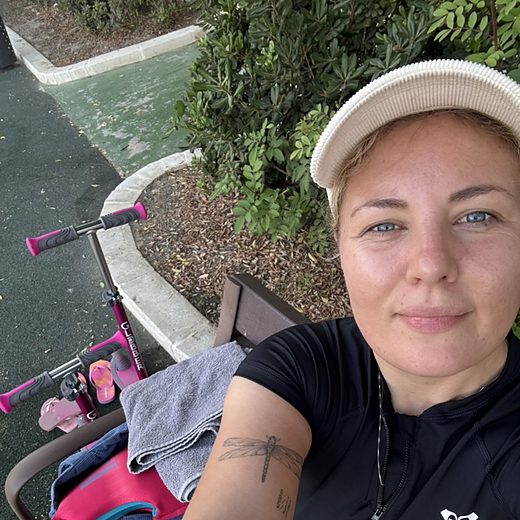 Jo Lina Fischer auf einer Bank am Spielplatz, daneben der Roller ihrer Tochter